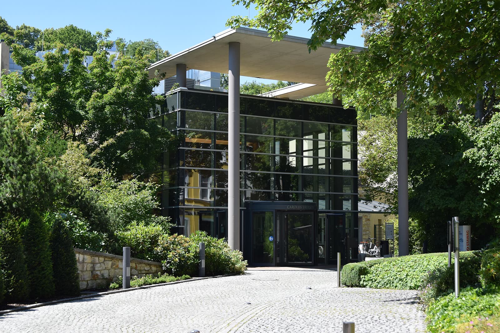 Green garden entrance and glass pavilion at Carolus Thermen in Aachen.