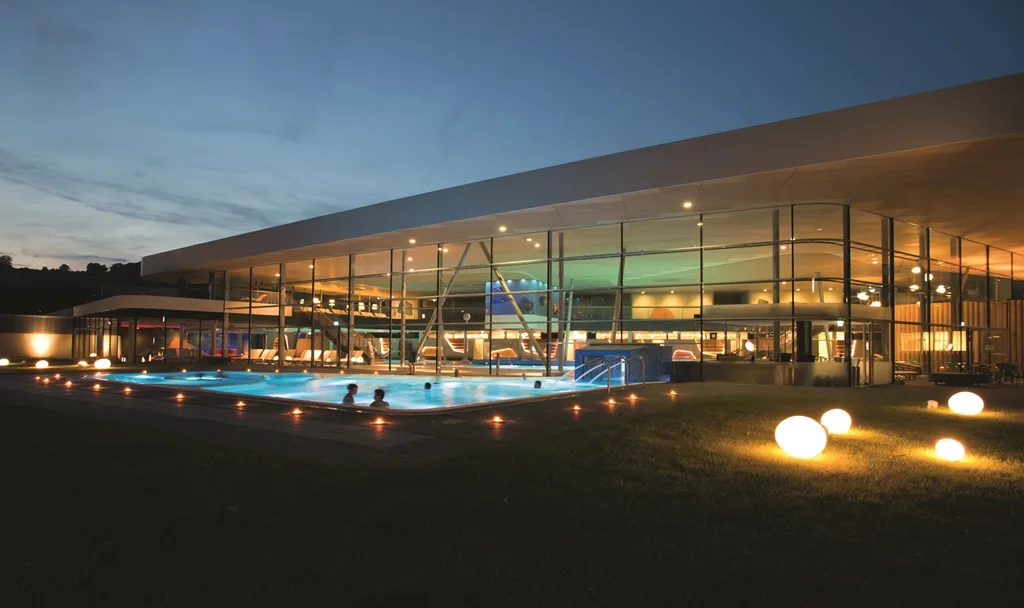 Emser Therme glowing beside its outdoor thermal pool at blue hour in Bad Ems.
