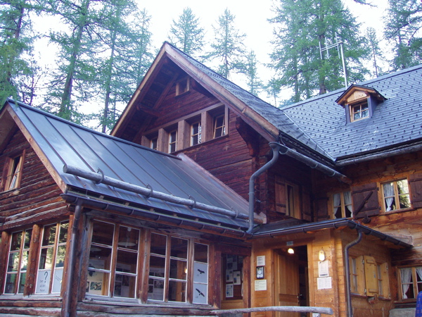 Chamanna Cluozza, a timber-and-stone hut in the forested Swiss National Park valley.